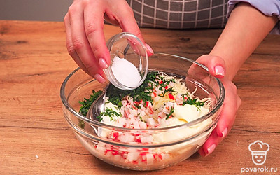 Приготовьте начинку. Мелко нарежьте крабовые палочки, яйца и зелень. Сыр натрите на мелкой терке. Добавьте майонез, соль и перец, перемешайте продукты.