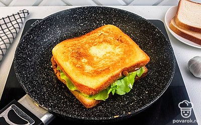 Соберите сэндвич: вверху на соус выложите лист салата, затем куриное филе, нарезанное на ломтики, помидор, снова лист салата и соус. Затем разогрейте сковороду с растительным маслом и обжарьте сэндвич по 2 минуты с каждой стороны до корочки.