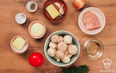 Подготовьте продукты для фаршированного блюда. Почистите шампиньоны, лук, чеснок, помойте помидор. Отделите ножки грибов от шляпок. Нарежьте на мелкие кубики куриное филе, ножки шампиньонов. Измельчите лук, чеснок. Помидор нарежьте круглыми кольцами толщиной 1 см. Натрите сыр на мелкой терке. Нарежьте сливочное масло кубиками. Для этого блюда лучше выбирать помидоры крупных сортов круглой формы с плотной кожицей.