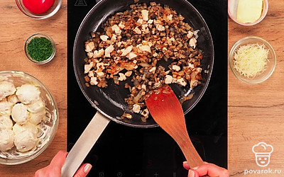 Приготовьте шампиньоны. Замаринуйте шляпки в майонезе 15 минут. Пока грибы маринуются, на растительном масле обжарьте 10 минут до золотистого цвета лук, ножки шампиньонов, чеснок и кубики куриного филе. Посолите, поперчите.