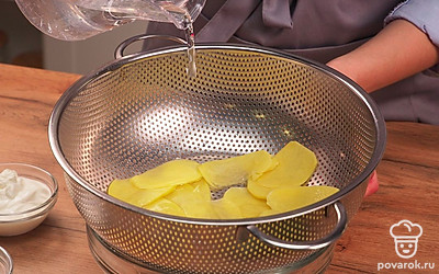 Подготовьте картофель для чипсов. Нарежьте тонкими ломтиками очищенный картофель. Можно натереть его на терке. Толщина каждого ломтика должна быть около 2 мм. Положите картофель в дуршлаг и промойте холодной водой. Дайте воде стечь.