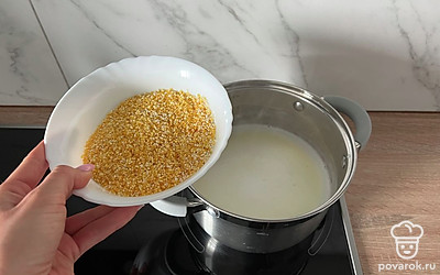 На среднем огне доводим жидкость до кипения и засыпаем промытую кукурузную крупу.