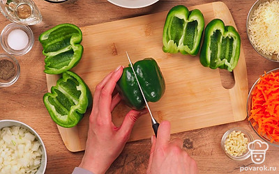 Промойте мясо и пропустите его через мясорубку. Вымойте овощи, очистите морковь, лук и чеснок, разрежьте перец пополам, удалите семена из перца. Мелко нарежьте лук и чеснок, сыр натрите на терке. Промойте рис. Приготовьте противень. Разогрейте духовку до 180 градусов.