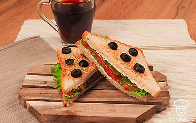 Разрежьте получившиеся сэндвичи по диагонали и подавайте, выложив на лист салата. Вкус лосося подчеркнут маслины. Если сэндвич плохо держит форму, проткните его шпажкой для канапе или зубочисткой.