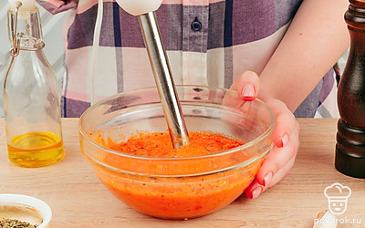 Добавьте к овощам соль и перец, перемешайте, снимите с огня и переложите в глубокую емкость. Измельчите смесь блендером до консистенции аджики.