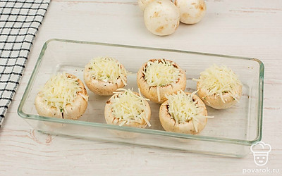 Шампиньоны с начинкой переложите на противень для запекания, смазанный маслом. Сверху грибы посыпьте сыром пармезан. Отправьте в духовку, разогретую до 180 ℃, оставьте запекаться на 10-15 минут.
