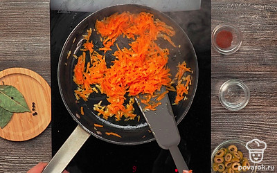 Приготовьте зажарку. На сковороде с растительным маслом обжарьте лук на среднем огне в течение 3 минут. Добавьте морковь и перемешайте. Уменьшите огонь и тушите ингредиенты 20 минут.