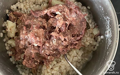 В горячую перловку ввести одну банку тушёнки, как следует перемешать.