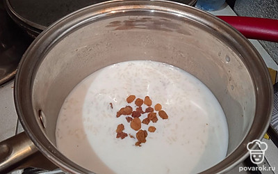 Влейте молоко и всыпьте изюм. Готовьте ещё примерно 10 минут.