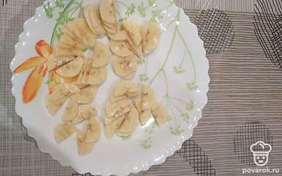 Банан нарежьте кружочками и добавьте в тарелку с кашей.