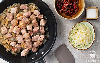 Подготовьте ингредиенты и обжарьте мясо. Свинину порежьте небольшими кусочками, репчатый лук измельчите, сыр потрите, вяленые помидоры нарежьте небольшими кубиками. В посуде с толстым дном сначала пожарьте на растительном масле мясо в течение 10 минут, затем добавьте лук и жарьте еще 5 минут до образования аппетитной корочки на мясе.