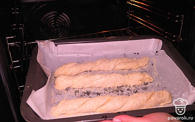 Переходите к завершающему этапу приготовления. Жгутики смажьте водой и посыпьте кунжутными семечками. Переложите на противень, застеленный пергаментной бумагой . Выпекайте при 220 ˚C 20-25 минут.