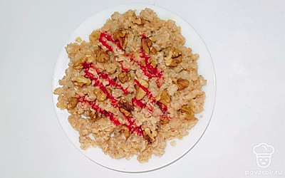 Украсьте овсянку с орехами и медом ягодами по вкусу. Сделайте рисунок ягодным соусом или джемом на ваш выбор.