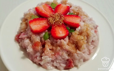 Выложите рисовую кашу на тарелку и украсьте ягодами клубники, разрезанными пополам. Посыпьте тростниковым сахаром и листиками мяты.