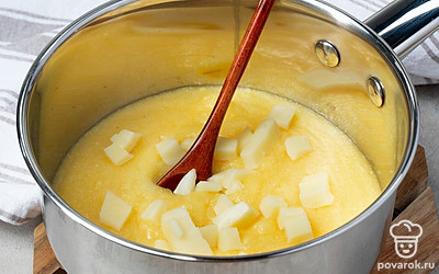 Приготовьте кашу. Добавьте в кастрюлю с крупой соль и сливочное масло. Порежьте сыр на кубики и выложите их в кашу. Хорошо все размешайте и варите еще пару минут на небольшом огне.