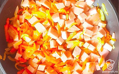 Лук, нарезанный четвертинками колец, а морковь – средними брусочками отправьте жариться в сковороду. Через 2 минуты добавьте к овощам нарезанную кубиками колбасу. Обжаривайте все до золотистой корочки.
