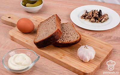 Яйцо сварите вкрутую: положите его в холодную воду и варите 8 минут после закипания. Готовое яйцо опустите в ледяную воду и очистите. Достаньте необходимое количество шпротов из банки и удалите с них масло с помощью салфеткии. Огурцы достаньте из банки и просушите бумажным полотенцем. Чеснок очистите.