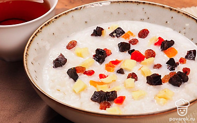 Разложите рисовую кашу по тарелкам, украсьте сверху изюмом и цукатами.
