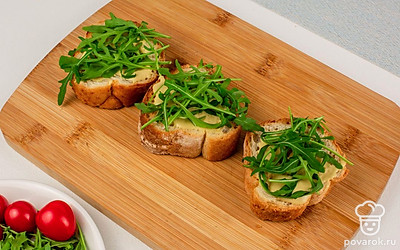 Выложите на соус руколу.