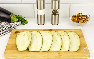 Нарежьте баклажаны тонкими пластинками. Залейте водой, посолите и оставьте на 10 минут, чтобы из них ушла горечь.