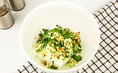 В глубокую тарелку добавьте творог, орехи и кинзу, хорошо все перемешайте.