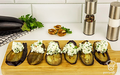 Готовые ломтики баклажана переместите на деревянную доску и выложите на них начинку. Аккуратно заверните рулетом.