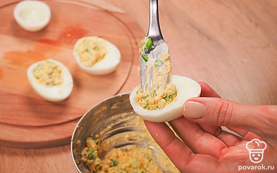 Нафаршируйте яйца. При помощи чайной ложки наполните половинки белков начинкой.