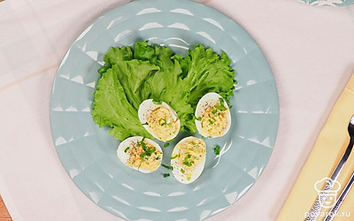 Сервировочное блюдо выложите листьями зеленого салата, разложите фаршированные яйца и подавайте к столу.