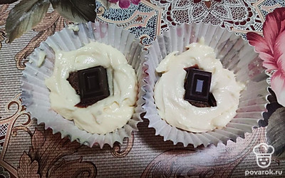 Выложите тесто в формочки на 1/3. Поместите в центр по дольке шоколада.