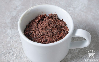 Переложите тесто в кружку, сверху посыпьте его шоколадом. Кружка должна быть заполнена на две трети, чтобы тесто не вывалилось в процессе выпекания.