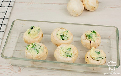 В шляпки грибов выложите начинку, затем переместите в форму для выпечки.