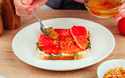 Намажьте хлеб, обжаренный на сухой сковороде, плотным слоем творожного сыра. Выложите на него рукколу и красную рыбу. Сверху смажьте всё дижонской горчицей.