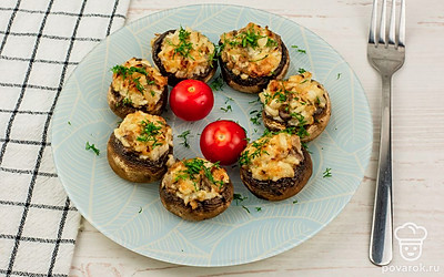 Готовые горячие шампиньоны переложите на тарелку для подачи. Украсьте сверху свежей, измельченной зеленью и помидорами черри.