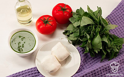 Помидоры нарежьте кружочками, моцареллу — тонкими ломтиками. Отделите от стебля листья базилика.