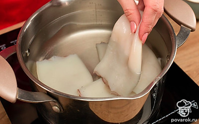 Филе кальмаров поместите в кастрюлю с холодной водой и отправьте на средний огонь. Когда вода прогреется, немного посолите, а когда закипит — тут же выключите и выловите тушки. Не переварите кальмары, иначе они станут жесткими. Лук очистите и нарежьте тонкой соломкой, мелко порубите грибы. Разогрейте духовку до 200°C.