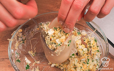 Запеките кальмаров. Тушки кальмаров заполните начинкой и выложите на пергамент. Сверху смажьте небольшим количеством сметаны. Выпекайте в разогретой до 150 градусов духовке в течение 15 минут.