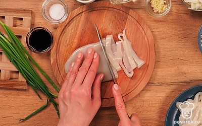 Удобно расположите все ингредиенты. Разморозьте кальмары, очистите их от кожицы, хорошо вымойте, нарежьте колечками шириной 3-4 мм. Очистите чеснок и лук от кожуры. Лук нарежьте тонкими дольками, чеснок — на мелкие кубики.