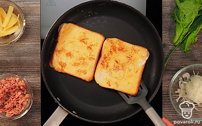 Подготовьте тосты из хлеба. Для этого разбейте в миску яйцо и взбейте его. Ломтики хлеба обмакните в яичную смесь, обжарте до золотистого цвета. Выложите на выстланную фольгой или пергаментом форму.