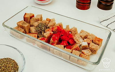 Нарежьте хлеб тонкими ломтиками примерно 1-1,5 см и поделите на кубики. Переложите его в форму для запекания или прямо на противень. Посолите и поперчите хлеб. Все хорошо перемешайте.