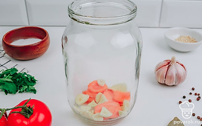 На дно порционной банки выложите морковь, чеснок, корень хрена, соль, острый перец, лавровый лист и зелень.