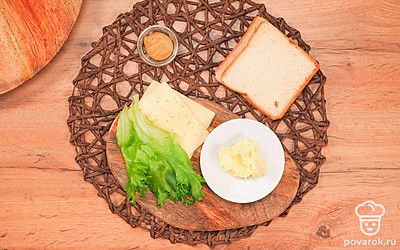 Подготовьте продукты и разложите их на столе. Сыр нарежьте тонкими слайсами, подходящими по размеру к кусочкам хлеба. Подготовьте сковороду для обжарки сэндвичей.