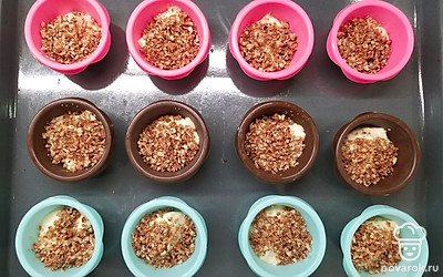 Заполните формы получившимся тестом наполовину, насыпьте в каждую по 1 ч.л. ореховой крошки. Выложите сверху еще тесто, наполнив формы на ¾, и снова посыпьте орехами. Поставьте кексы в разогретую духовку и выпекайте 30 минут.