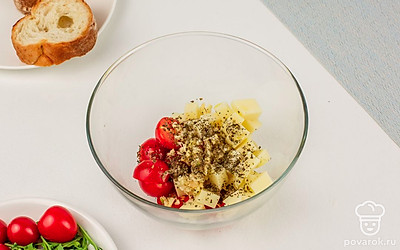 В глубокой миске смешайте помидоры черри и сыр. Заправьте всё оливковым маслом, выдавите зубчик чеснока, добавьте прованские травы, посолите и поперчите. Перемешайте.