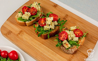 Сверху выложите начинку из сыра и томатов. Брускетты готовы.