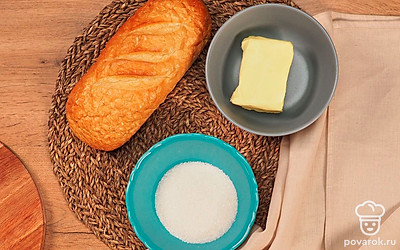 Достаньте масло из холодильника заранее, чтобы оно стало мягким. Включите духовку и нагрейте ее до 120℃.Нарежьте батон на кусочки толщиной 1-1,5 см. Застелите сухой противень бумагой для выпечки.