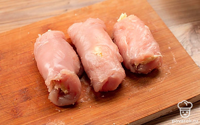 Посолите и поперчите куриное филе, выложите на каждую часть майонезную массу и закрутите в плотные рулеты.