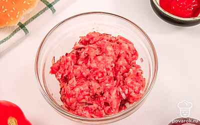 В глубокой миске соедините говяжий фарш, измельченный красный лук и одно яйцо. Посолите и поперчите по вкусу. Тщательно все перемешайте до однородной консистенции.