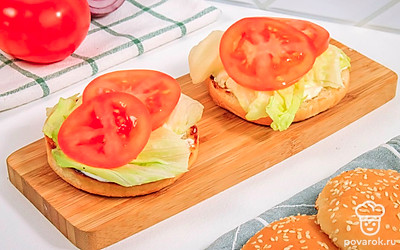 Выложите на булочки листья салата и ломтики помидоров.