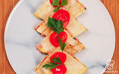 Украсьте готовое блюдо перед подачей: разложите нарезанные куски на широком блюде, положите на каждый кусочек по кружочку помидора и украсьте веточками укропа или петрушки.