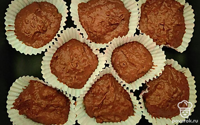 Получившуюся массу распределите по формам для кексов на 2/3 и отправьте запекаться в разогретую духовку до 180 °C на 18-20 минут. Готовность кексов проверьте зубочисткой или шпажкой. Шоколад растопите на водяной бане или в микроволновке. Остывшие кексы смажьте сверху растопленным шоколадом.